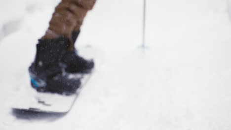 Hombre-En-Splitboard-Levantando-Nieve-En-Polvo-Y-Luego-Empujando-Postes-Para-Despegar-Por-Un-Sendero-Nevado