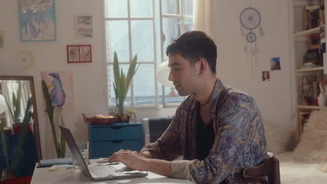 young man typing on laptop at home