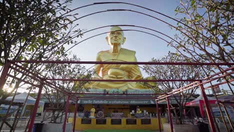 4k panorámica hacia atrás desde una estatua dorada de un monje luang pu thuat