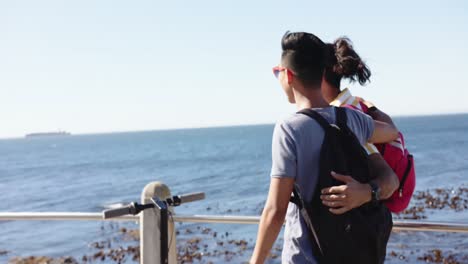 happy diverse gay male couple embracing at promenade by the sea, slow motion