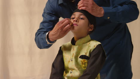 Foto-De-Estudio-De-Un-Padre-Atando-Un-Turbante-En-La-Cabeza-De-Su-Hijo-Sikh-Que-Lleva-Un-Chaleco-Tradicional,-Como-Se-Muestra-En-La-Secuencia,-Parte-8-De-10