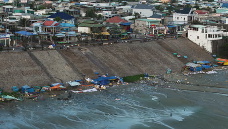 un pueblo de pescadores lleno de desechos marinos de plástico en la orilla durante la marea baja, pan de telefotografía aérea