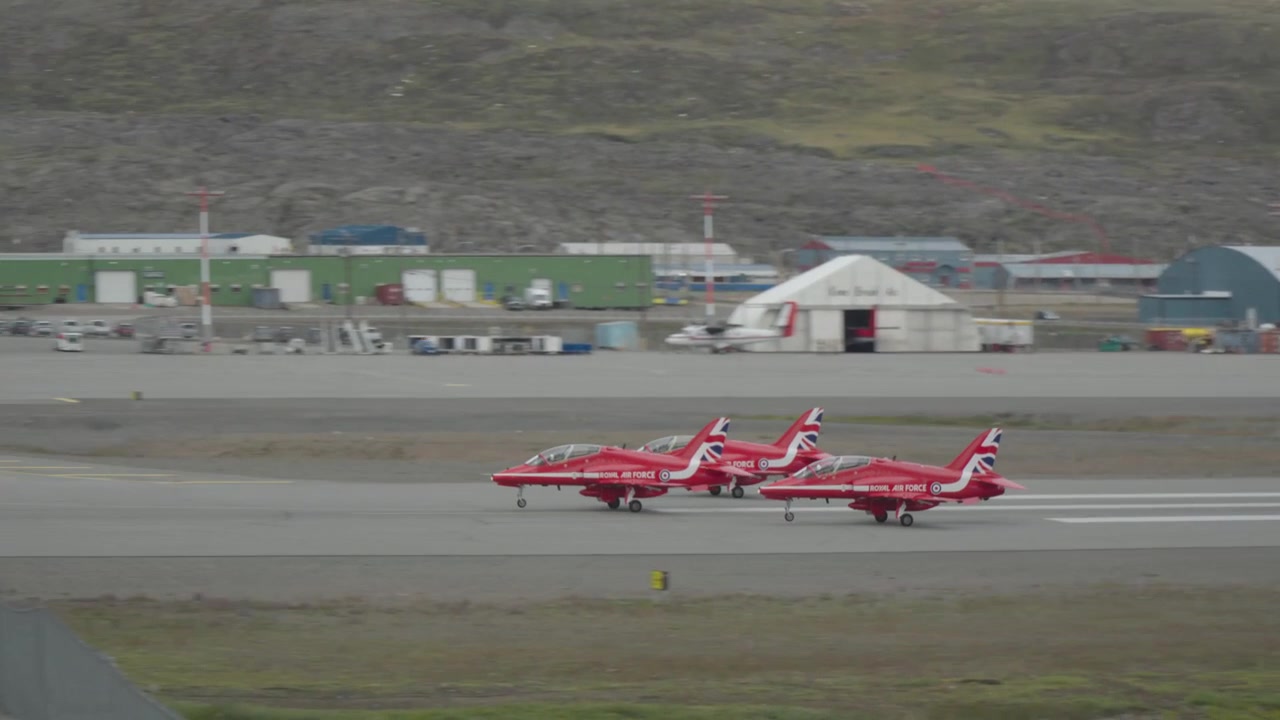 Vista ravvicinata con teleobiettivo che si concentra su tre jet BAE Hawk degli RAF Red Arrows che accelerano in formazione stretta e decollano insieme dalla pista di Iqaluit.