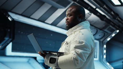 vertical video astronaut crew inside futuristic spacecraft monitoring mission data on laptop