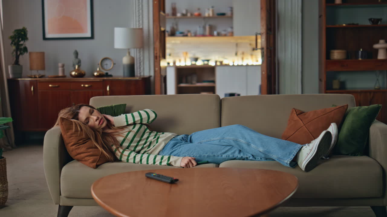 Exhausted woman lying sofa looking smartphone after long day. Girl resting couch