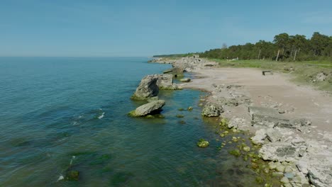 Beautiful-aerial-establishing-view-of-Karosta-concrete-coast-fortification-ruins,-calm-Baltic-sea,-sunny-summer-day,-wide-drone-shot-moving-forward-low