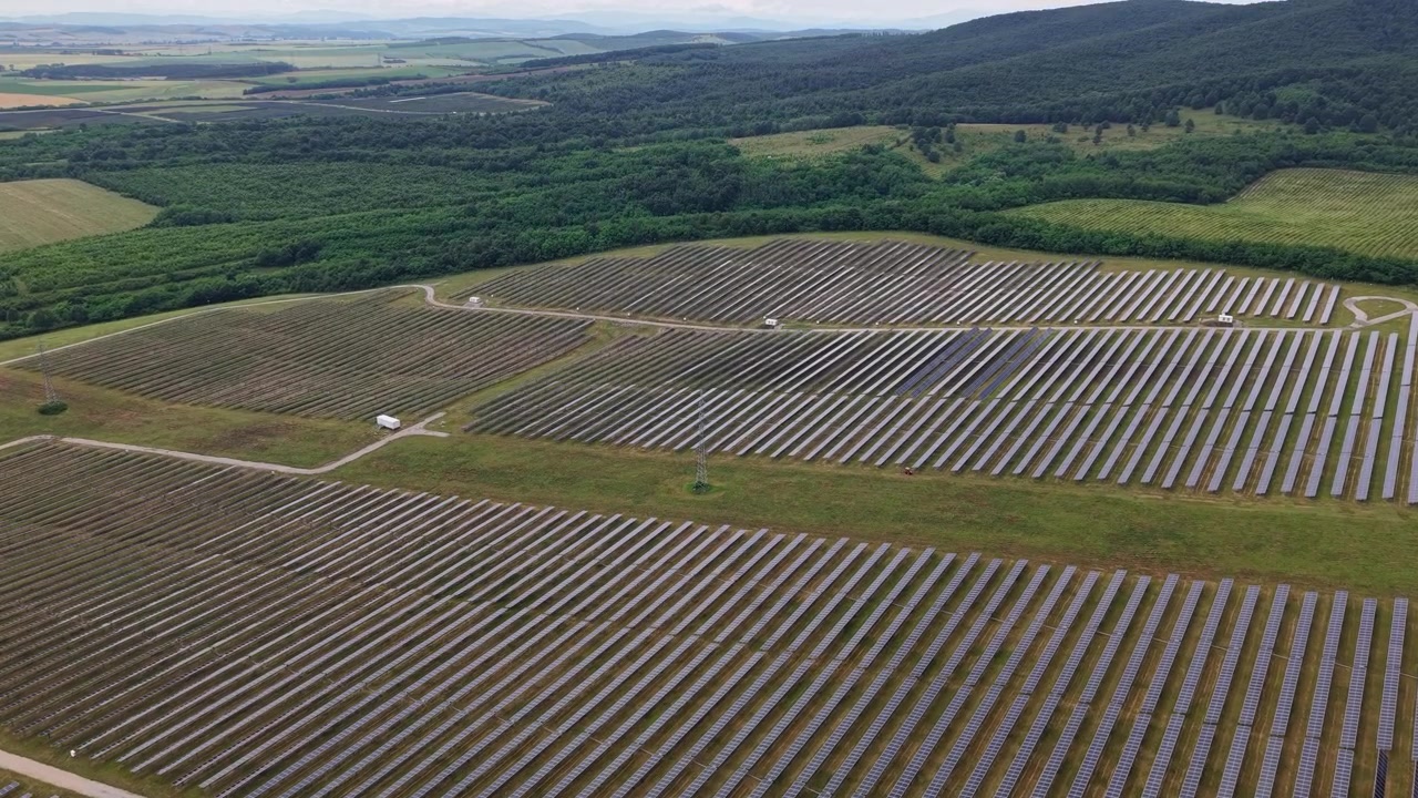 Et omfattende luftfoto af en stor solcellepark beliggende i Ungarns landlige landskab, der repræsenterer grøn energi.