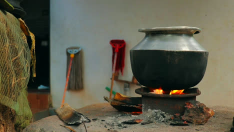 a aluminium pot is placed on a traditional fireplace with burned woods