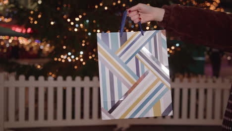 special christmas present held in front of christmas tree