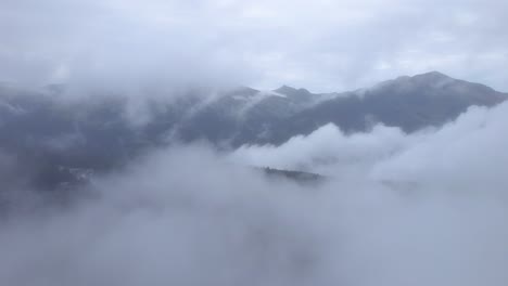 drone flying through the clouds discovering a mountainous landscape in the distance