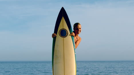 female surfer peeking from behind her board