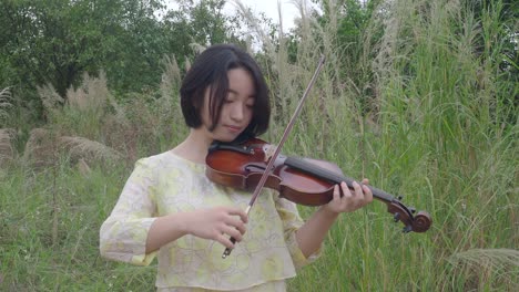 adolescente asiática tocando el violín