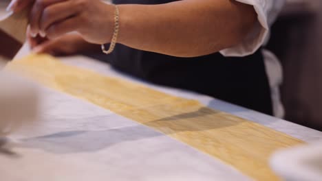 Tight-shot-of-female-chef-brushing-handmade-lasagna-in-kitchen