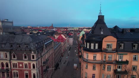 drone shot revealing the cityscape of stockholm old town, colourful swedish buildings architecture with busy streets, cathedral in the evening