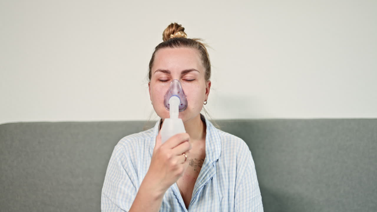 Žena s dusivým kašlem je léčena doma dýcháním přes nebulizátor. Samoléčba kašle doma pomocí inhalátoru.