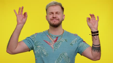 stylish man breathes deeply with mudra gesture meditating with concentrated thoughts, peaceful mind