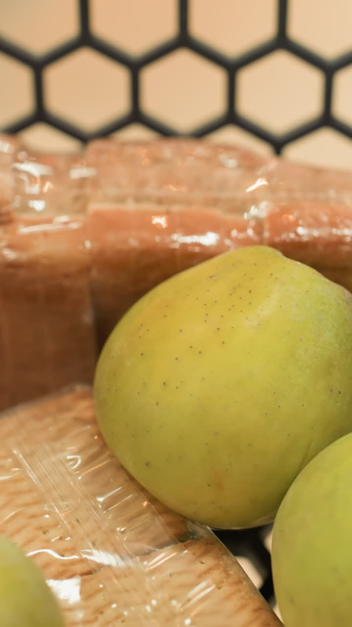 vista de cerca de una mano colocando plátanos en un carrito de compras que ya contiene un paquete de galletas, un pequeño jugo, un pan y varias manzanas
