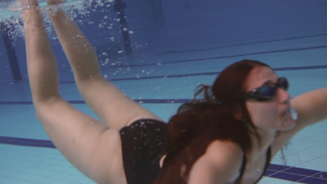 Underwater-Shot-Of-Woman-Swimming-In-Indoor-Pool