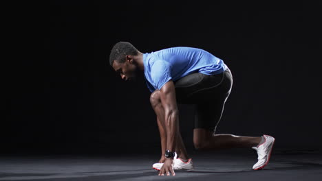 african american athlete man in a runner's starting position on a black background