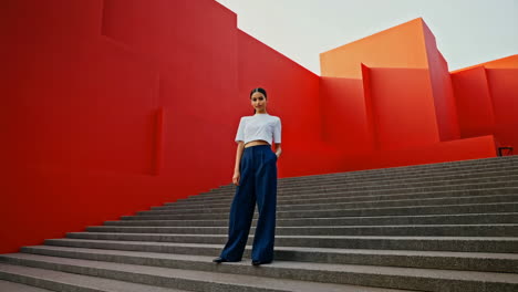 woman posing on modern stairs with red and orange walls
