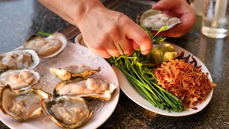 hands garnishing oysters with herbs and spices