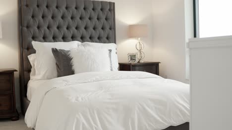 modern bed with a tall grey headboard and white bedding