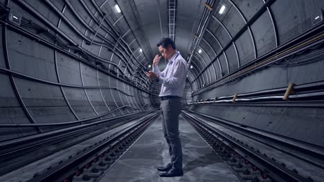 full body side view of an asian male professional worker standing with his phone in underground subway tunnel, he is nodding his head with dissapionted