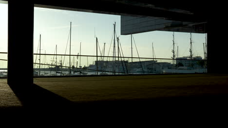 silhouetted view of a harbor with yachts and masts framed by architectural elements