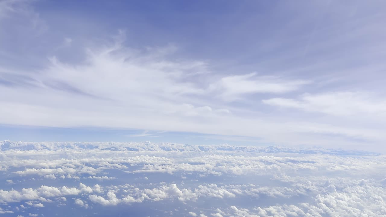 Footage showing clouds in the sky as seen from an airplane window, capturing aerial atmospheric views, soft white formations, and a serene blue horizon, ideal for travel, aviation, and nature visuals