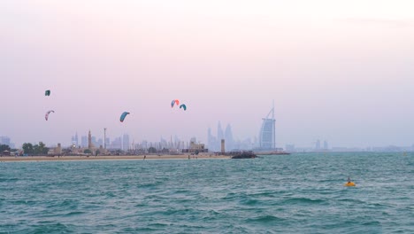 Surfistas-Con-Cometas-De-Colores-En-La-Pintoresca-Playa-De-Agua-En-Dubai,-Jumeirah,-Emiratos-árabes-Unidos