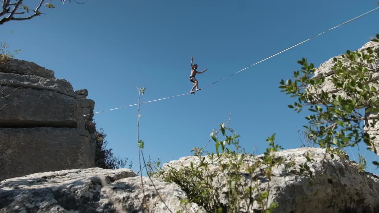 toma de cardán de hombres en un slackline en la cima de una montaña