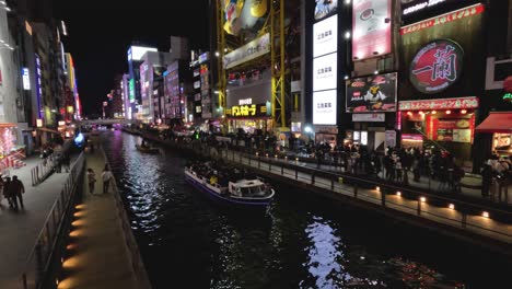 boat glides along a canal in a vibrant, illuminated city.