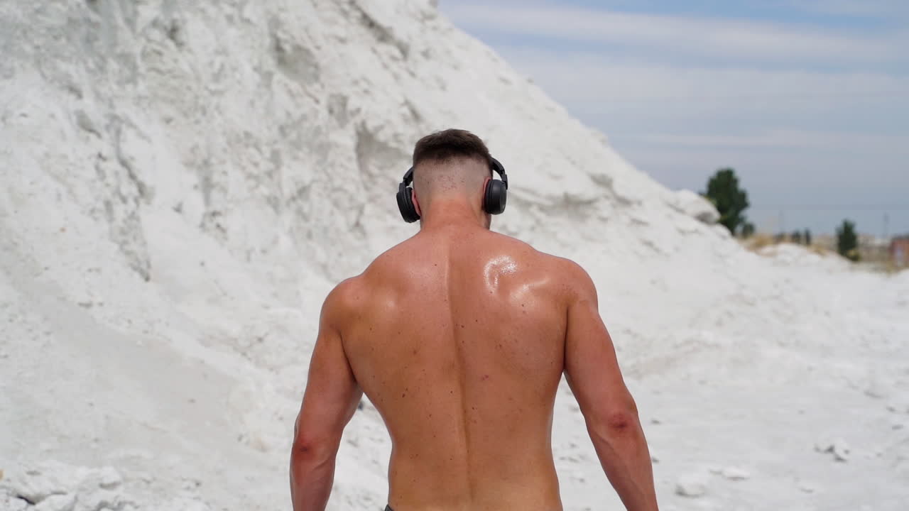 Sportsman listening music for workout. Rear view of sportman listening music with wireless headphones at training
