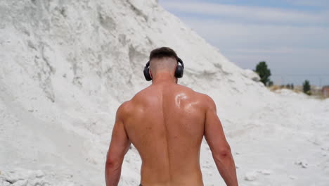 sportsman listening music for workout. rear view of sportman listening music with wireless headphones at training