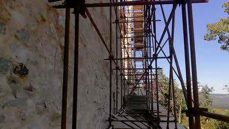 metallic scaffolding against an old ruins wall, tilt up