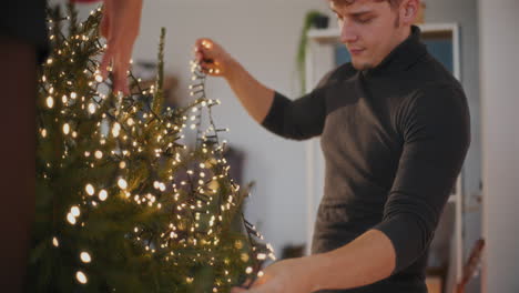 pareja con luces led decorando el árbol de navidad