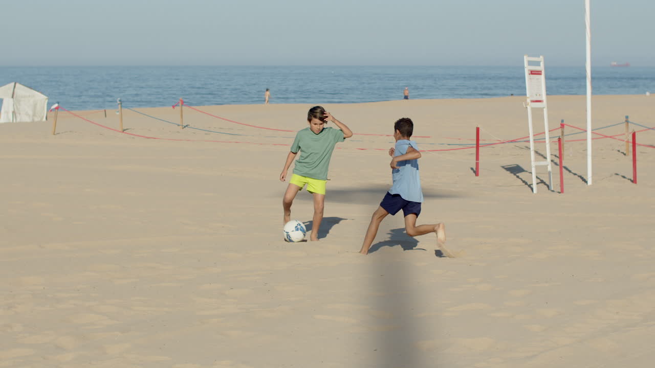 una foto larga de adolescentes felices jugando al fútbol en una playa de arena