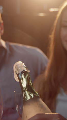 grupo de amigos sonrientes interactuando mientras tienen un vaso de champán en la barra