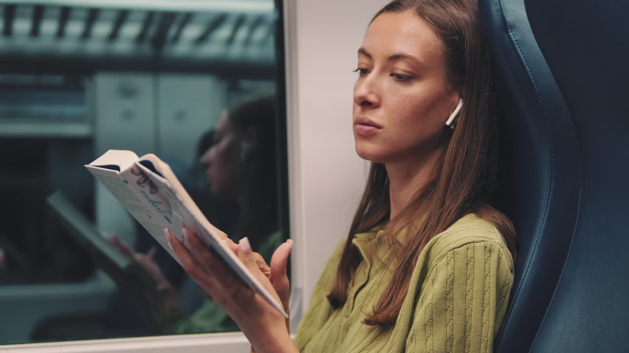 Young Woman Reading a Book While Traveling on a Train