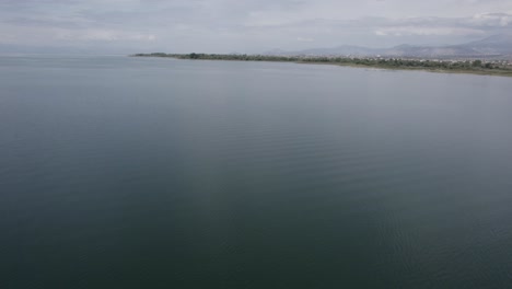 Video-with-a-drone-over-Lake-Skadar-in-Albania,-descriptive-frontal-plane-advancing-with-the-Grude-Fushe-village-on-the-horizon-with-the-mountains