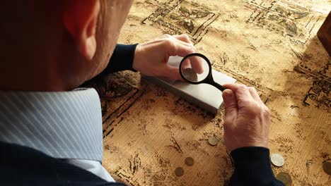 coin evaluator. the collector of coins. the man considers ancient coins.