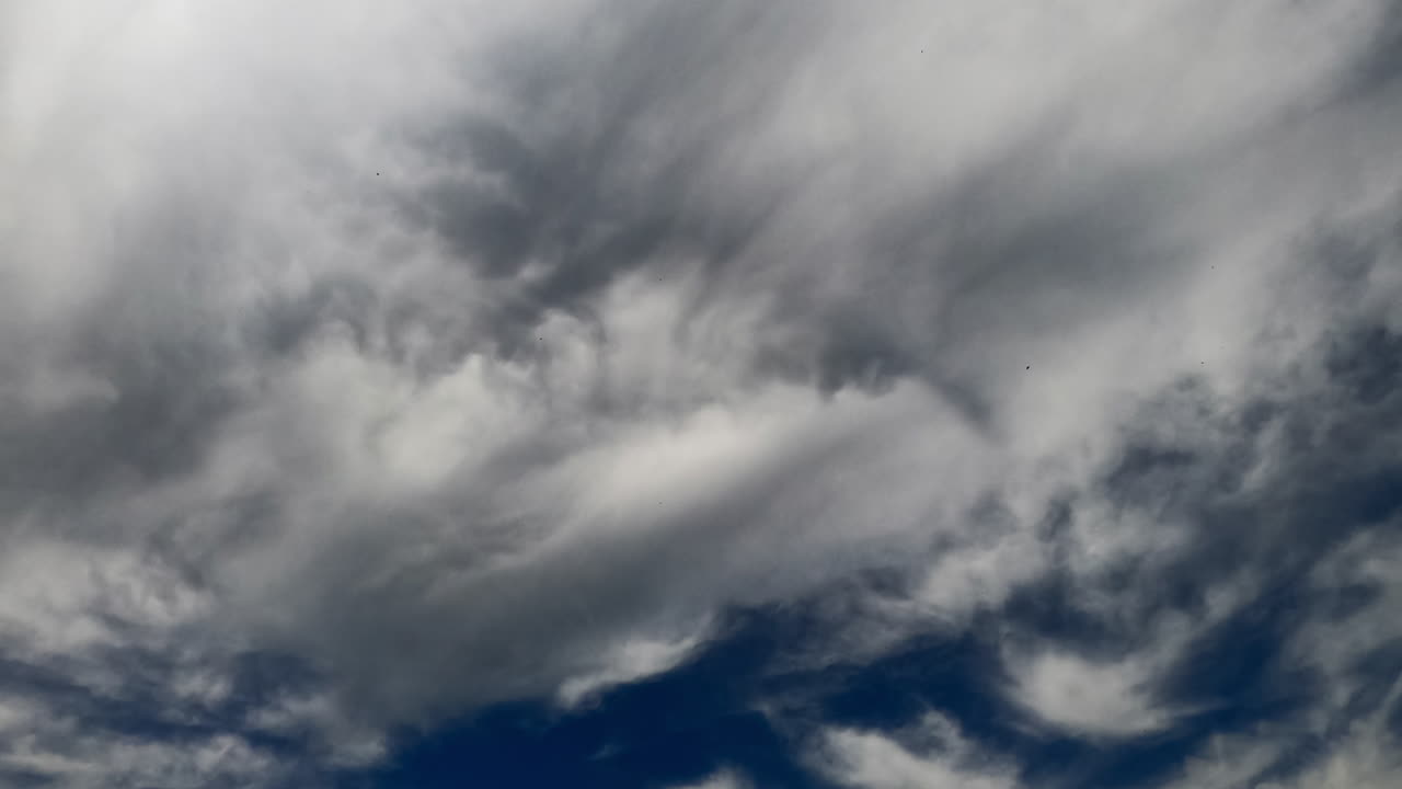 Clouds transforming in the atmosphere. Grey cloudscape gathering in the sky forming rain. Low angle view timelapse.