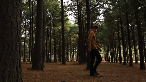 A-man-in-a-gold,-yellow-hoodie-walking-casually-through-the-forest-wearing-sunglasses-and-black-pants-on-a-peaceful-afternoon-in-Jacobson-Park-Lexington-Kentucky