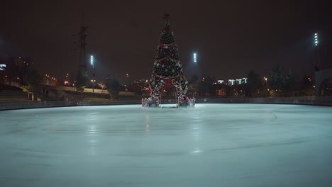christmas ice rink with decorated xmas fir tree empty during quarantine pandemic coronavirus and covid 2019 in the evening in ukraine, kiev. ice rink at night. empty public place for skating