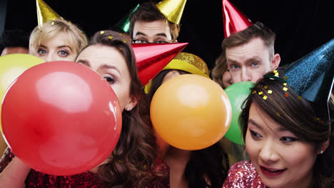 grupo multi-racial de amigos soplando globos cámara lenta de la fiesta cabina de fotos