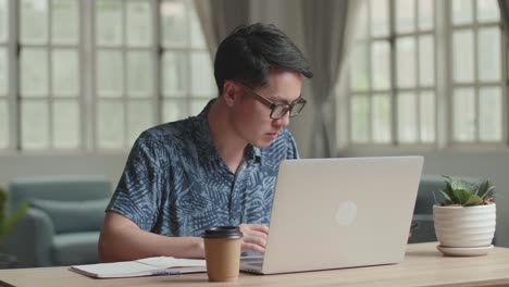 male talking on phone during work with laptop computer and writing on notebook at home, video in 4k