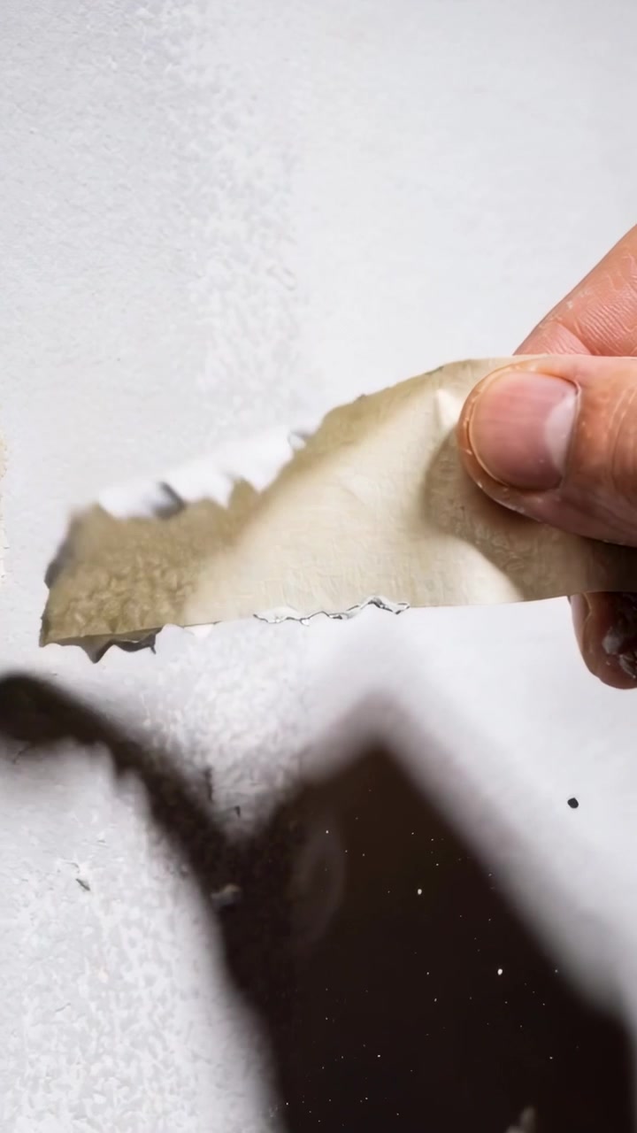 Vertical video: Pulling hand from right peeling strip from wall at home for repair, leaving flakes