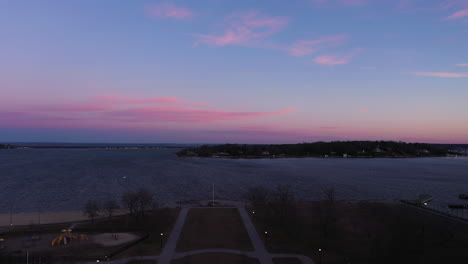 an aerial shot over an empty park focused on the bay during a beautiful sunrise