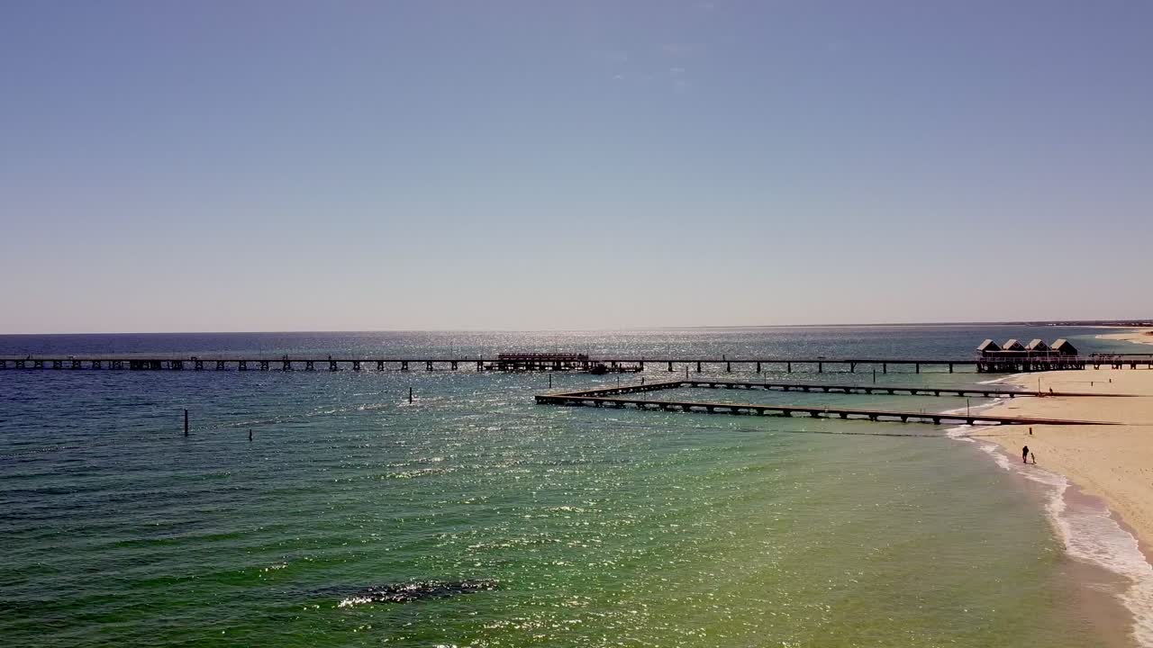 Long Pier Stretching into the Ocean from a Sunny Beach
