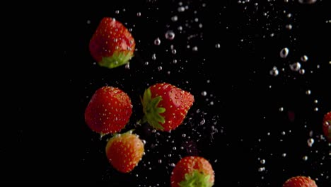 Erdbeeren-Fallen-Ins-Wasser-Super-Slowmotion,-Schwarzer-Hintergrund,-Viele-Luftblasen,-4k240fps